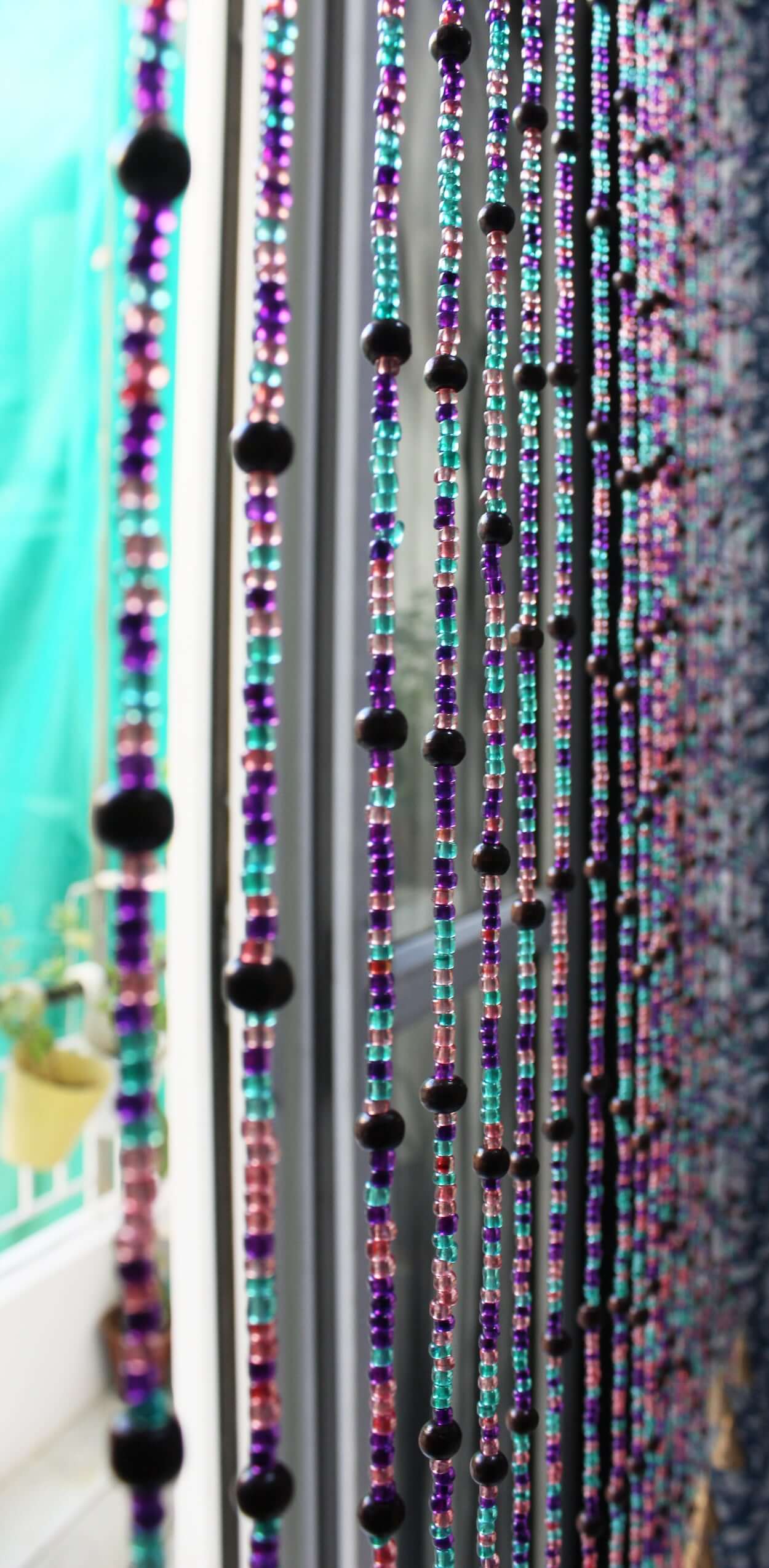 Handmade colorful glass bead strands with jingle bells—perfect for doorways or wall décor. Eco-friendly and crafted by women's artisans in India.